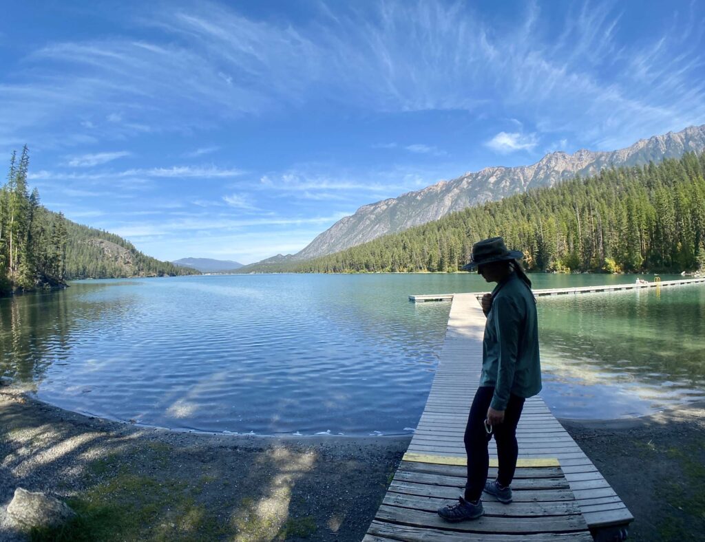 This image includes a woman standing on a jetty at a mountain lake.