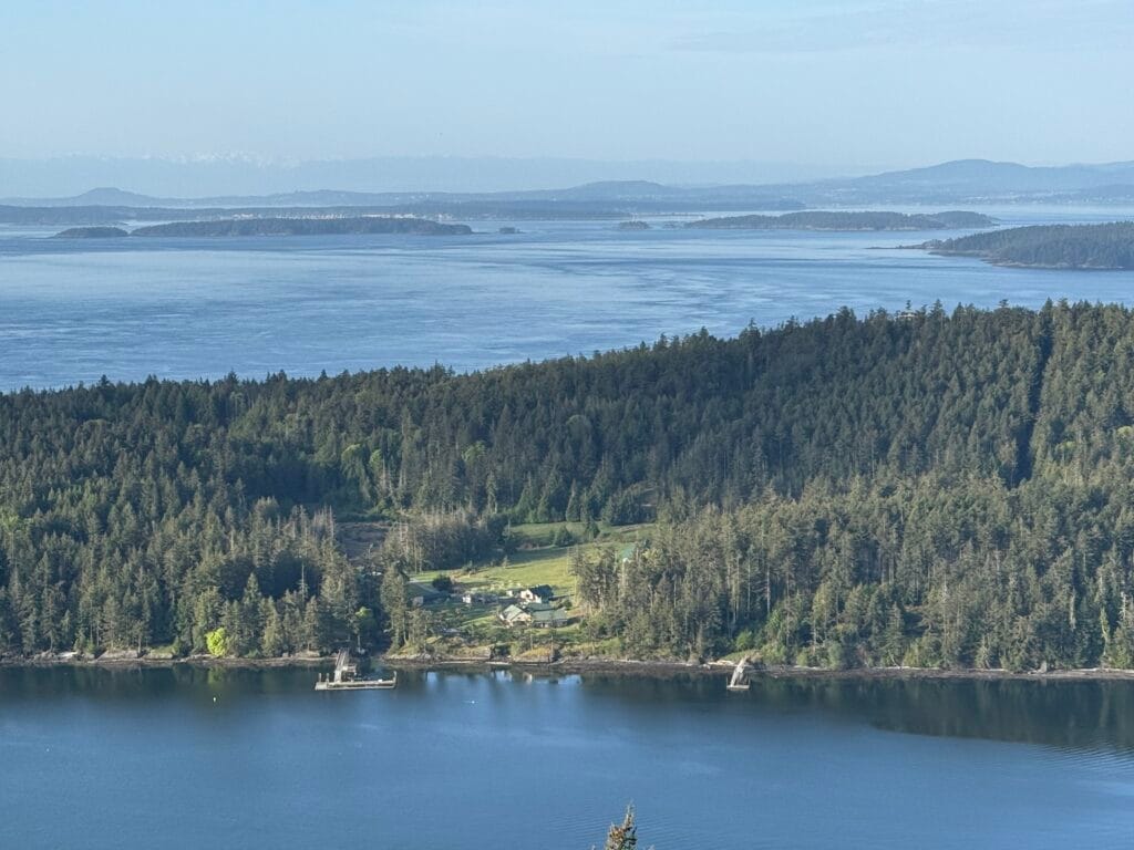 Standing at the Smonecten Campground , you look down upon a combination of blue sky and tree-covered Gulf Islands.