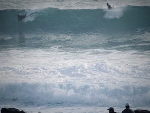 In this image, surfers test their boards in tumultuous breaking waves. In this setting, you could envision that with every crashing wave, a deeper sense of relaxation is achieved.