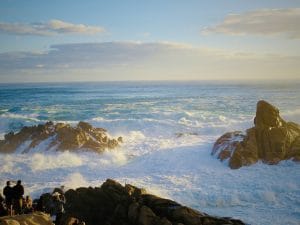 The ocean can captivate the human imagination. This image is a seascape with people who are drawn to observe the turbulent ocean.